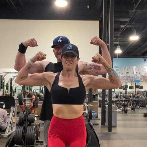 Jenn and Geoff flexing their biceps in the gym