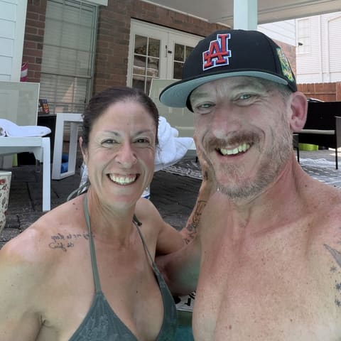 Jenn and Geoff smiling together in the pool on a sunny day